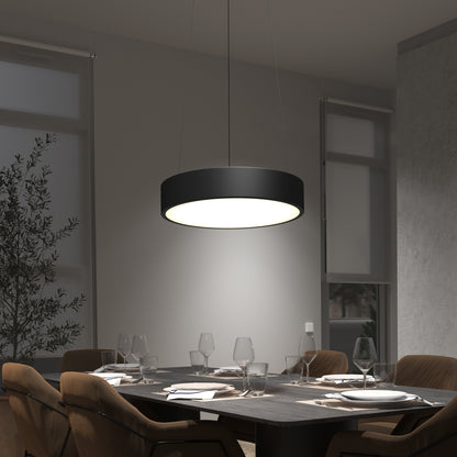 A modern dining room features a dark rectangular table set for six with brown chairs. Above, the Concerto LED Pendant softly lights the space. Large windows and a potted plant appear in the background.