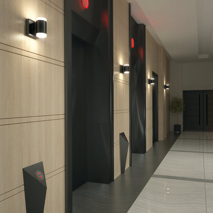 Modern hallway with three closed elevator doors, each showing a red up arrow. Light wood-paneled walls, glossy tiled floor, Neo LED Indoor/Outdoor Wall Lights on walls, and a potted plant at the corridor’s end.