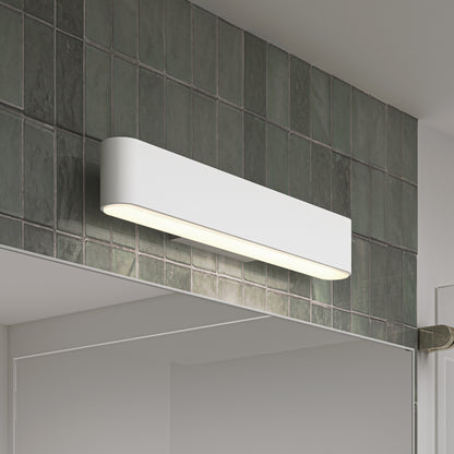 The Willow LED Vanity 3CCT Light with rounded edges is mounted above a bathroom mirror on dark green square tiles, illuminating the space below with adjustable color balance for perfect lighting.