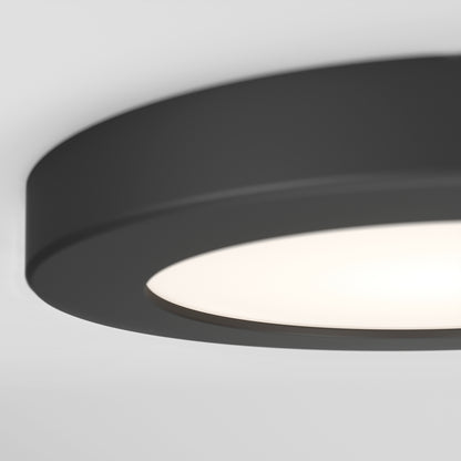 Close-up of the Skylight Pro 5 3K LED Flat Panel Light, a modern, ultra-slim, circular black ceiling fixture with a glowing white center, mounted on a white ceiling.