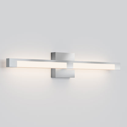 The Tivoli 27'' Vanity Light is a modern wall-mounted fixture with a sleek, horizontal metallic silver design that emits a soft white glow from both sides against a light gray wall.