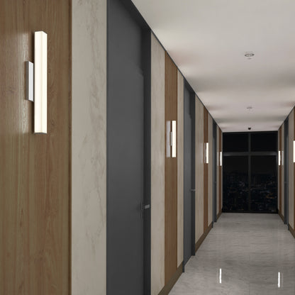 A modern hallway features wood and marble panel walls, gray doors, a shiny marble floor, and Mylo LED Vanity Light 16IN wall-mounted vertically. A large window at the end reveals a nighttime city view.