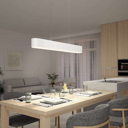 A modern dining area features a light wood table set for four with gray chairs. The centerpiece is the Willow LED Pendant hanging above. In the background are a sofa, plants, and large windows with sheer curtains.