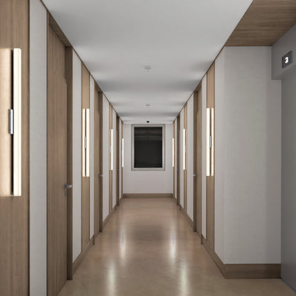 A modern hallway features wooden doors, beige flooring, a window at the end, and Mylo LED Vanity Light 36IN fixtures beside each door. An elevator on the right displays a lit number 3.