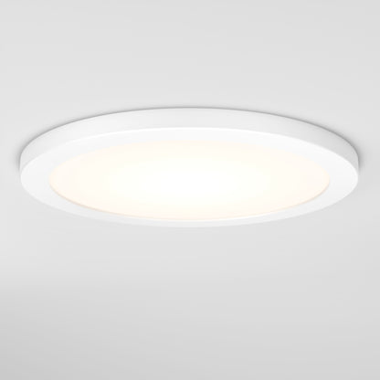 The Skylight Pro 12 3K LED Flat Panel Light, a round, white, flush-mounted ceiling fixture, shines gently on a plain white ceiling and creates a soft, even glow.