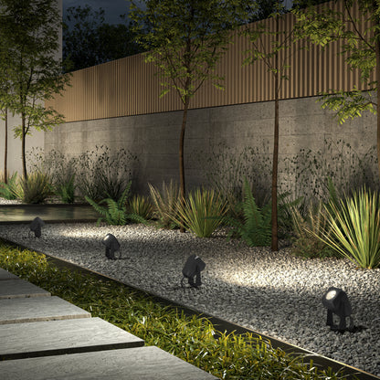 A stone path lined with small elephant statues, illuminated by Verner Plug-in Landscape Single CCT LED 4-pack lights, creates a charming scene in the garden.