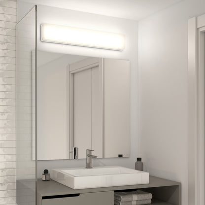 A modern bathroom with a rectangular sink, sleek faucet, wall-mounted mirror, and the Aster 27in Energy Star LED Vanity Light above; toiletries like soap and a small towel rest on the gray countertop.