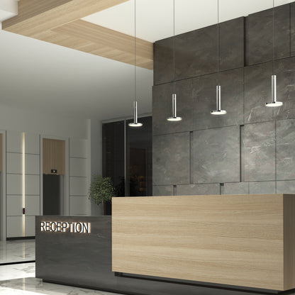 Modern hotel reception area with a wooden and dark stone counter, illuminated "RECEPTION" sign, marble floor, potted plant, elevator doors, and Romeo 1-Light LED Pendant lights hanging from the ceiling.