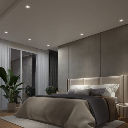 A modern bedroom with a large bed, neutral bedding, and cushioned headboard features floor-to-ceiling windows, white curtains, a tall green plant, and cozy Skyview 4in Gimbal Round, 5CCT LED lights for an elegant atmosphere.