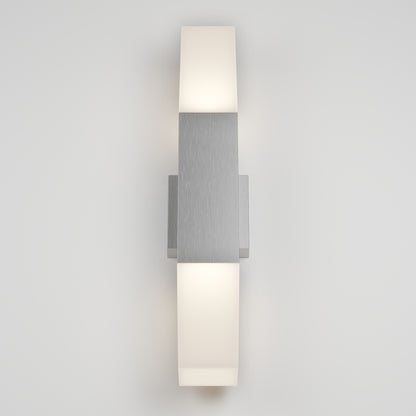 The Lennox Pro LED Outdoor Wall Light features a brushed metal center with frosted white diffusers on the top and bottom, mounted on a plain light gray wall and illuminated.