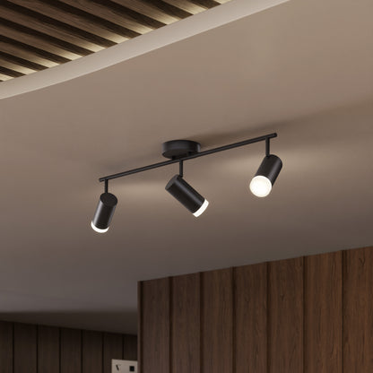 The 32" Blake 3L tracklight is a modern black LED fixture with three adjustable cylindrical lights, perfect for versatile task lighting on a white ceiling accented by wood panels and slatted details.