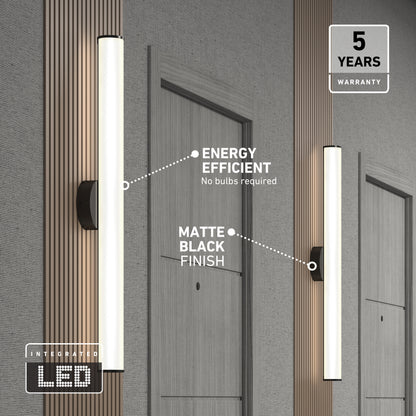 A modern hallway features Kalio Indoor LED Wall Sconce 32" in matte black. Energy-efficient integrated LED (no bulbs needed), 0-10V dimming, 120-277V, and a 5-year warranty. Doors with room numbers are visible in the background.