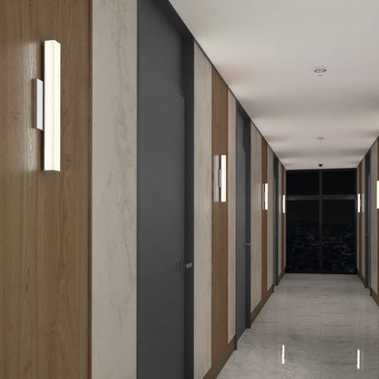 A modern hallway features light wood and marble wall panels, gray doors, shiny marble floors, and Mylo LED Vanity Light 16IN fixtures. Windows at the end display a night cityscape.