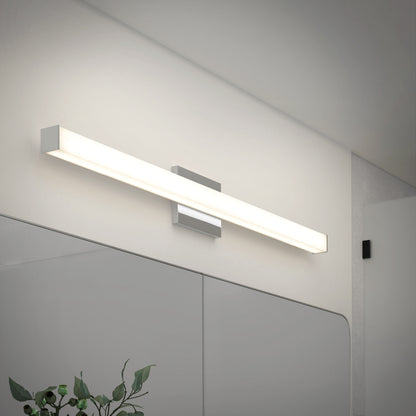 The Mylo LED Vanity Light 36IN, featuring a minimalist rectangular design, is mounted above a large mirror in a modern bathroom. A leafy plant appears in the corner, while the fixture creates a soft, ambient glow.