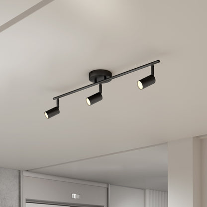 The 32" Rowen 3L tracklight, a modern black fixture with three adjustable spotlights, is mounted on a white ceiling in a minimalist room.