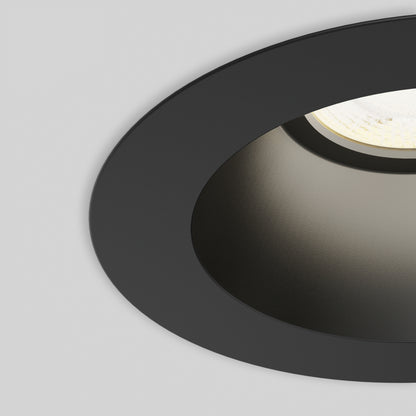 Close-up of the Skyview 4in Regressed Round, 5CCT LED pot light with a black finish and white inner surface, partially illuminated against a white ceiling—ideal for sleek, modern recessed lighting.