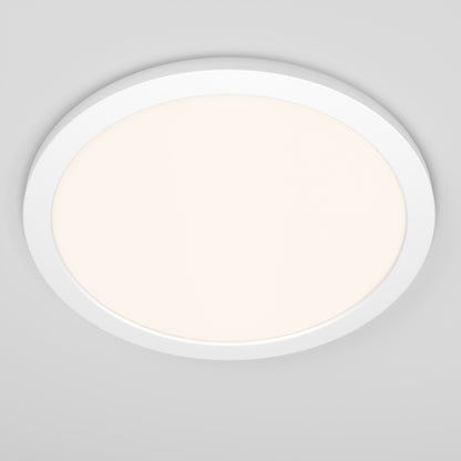 The Skylight Pro 15 5K LED Flat Panel Light, round and white, emits a soft, diffused glow and is mounted on a plain light gray ceiling.