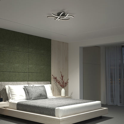 Modern bedroom with a low wooden bed, gray and white bedding, green padded wall panels, a vase with branches on the bedside table, and a Dillon LED Flush Mount Noir ceiling light. Floor-to-ceiling curtains cover large windows.