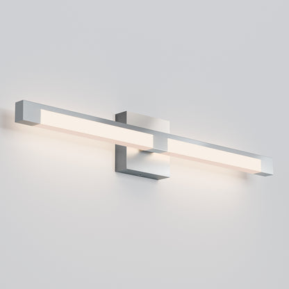The Tivoli 27'' Vanity Light is a modern, wall-mounted fixture with a sleek horizontal rectangular design and brushed metal finish, casting a soft, even glow on a light gray wall.