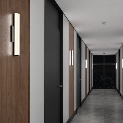 A modern hallway with wooden and white paneled walls, black doors, and Mylo LED Vanity Light 16IN illuminating the space, leading to a large window revealing a nighttime cityscape.