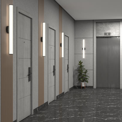 Modern apartment hallway with three light wood doors on the left, a gray elevator marked 3 on the right, marble floor, and Kalio Indoor LED Wall Sconce 32" lights on the walls. A potted plant sits near the elevator.