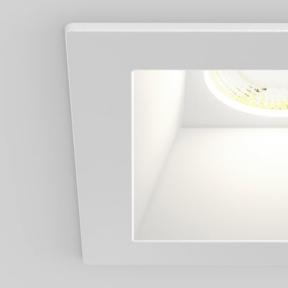 Close-up of the Skyview 4in Regressed Square, 5CCT LED—a modern square recessed pot light with a white frame and visible bulb, offering adjustable color temperatures for versatile indoor or outdoor lighting. Set against a plain gray background.