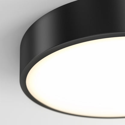 Close-up of the Concerto LED Flush Mount, a modern round black ceiling light with a bright white illuminated surface, shown against a plain white background.