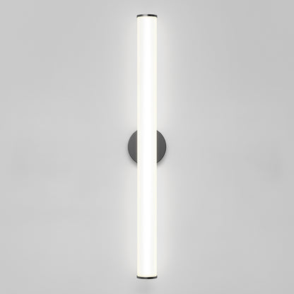 The Kalio Indoor LED Wall Sconce 32" features a cylindrical design emitting bright white light, wall-mounted on a round black base against a plain light gray wall. Suitable for 0-10V dimming at 120-277V.