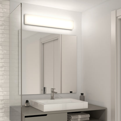 A modern bathroom with a rectangular sink, wall-mounted faucet, and mirror, illuminated by the Aster 27in Energy Star LED Vanity Light above the mirror. Towels and toiletries are neatly arranged on the countertop.