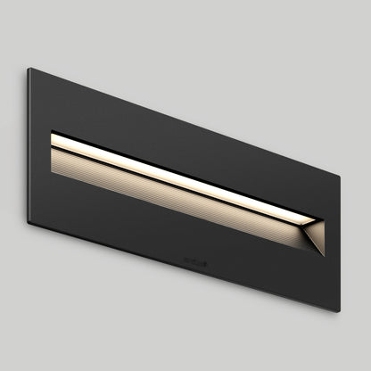 The Dark Sky Step Light Pro- Black 12in is a rectangular wall-mounted LED fixture with a horizontal slit that emits soft white light, shown against a plain, light gray background.