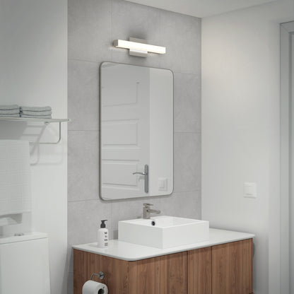 Modern bathroom with a wooden vanity, square sink, large rectangular mirror, and the Mylo LED Vanity Light 16IN overhead. A shelf holds folded towels; soap dispenser and toilet paper are seen on the counter and holder.
