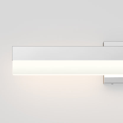 The Mystic LED Vanity Light is a modern, rectangular wall-mounted fixture with a minimalist design, casting a soft white glow against a light gray wall.
