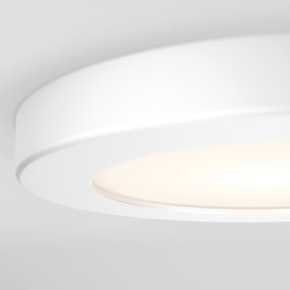 Close-up of the Skylight Pro 5 3K LED Flat Panel Light, a modern circular fixture with smooth, rounded edges and a minimalistic design, softly illuminating a white ceiling with diffused white light.