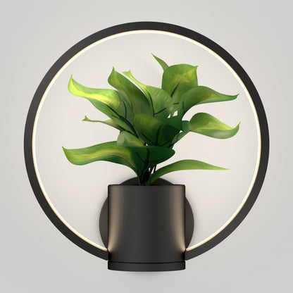 The Halo Planter LED wall sconce features a modern black planter with lush green foliage, highlighted by a circular LED light ring and set against a plain white background.