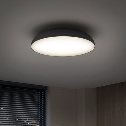 The Flint LED Flush Mount brightens a room featuring white walls and a window with horizontal blinds.