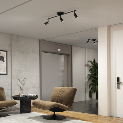 Modern lobby with gray walls, two brown swivel chairs, a small round table with a vase, 32" Rowen 3L tracklight on the ceiling, a tall plant, and an elevator door in the background.